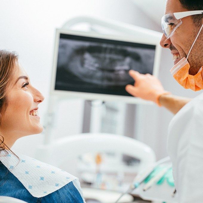 Smiling woman and dentist looking at x-rays