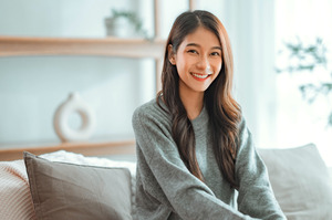 Woman sitting up straight on bed and smiling