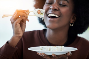 Woman with fantastic veneers about to eat a sushi